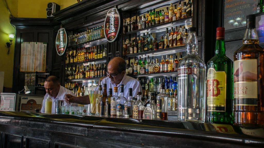 The back bar spirits wall at Timba Social Club, lined with rum, agave, and liqueur bottles.